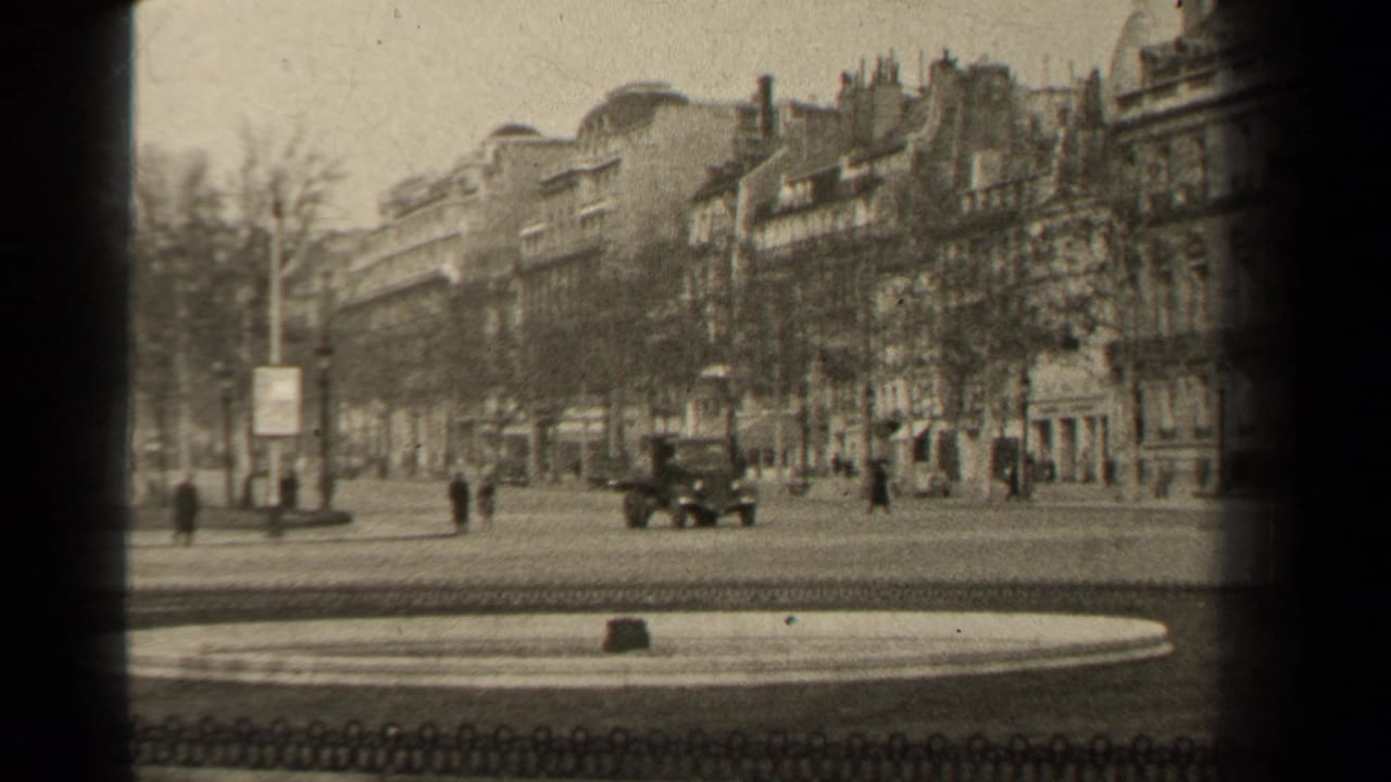 A car crosses a city street with pedestrians and tall buildings behind it.