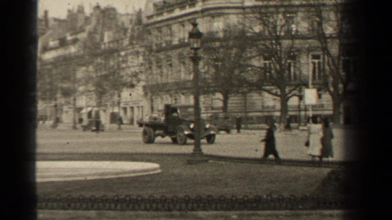 A 1947 Paris street view with pedestrians in long coats, a passing vehicle, a lamppost, bare trees, and stone facades in soft 8mm focus.