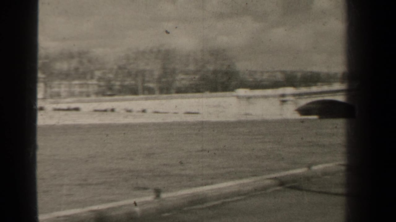 1947 Paris river embankment view with open water, paved foreground, distant trees, and part of an arched bridge at the right edge.