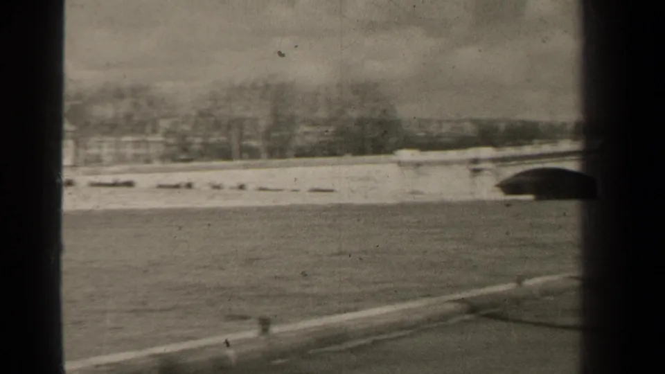 1947 Paris river embankment view with open water, paved foreground, distant trees, and part of an arched bridge at the right edge.