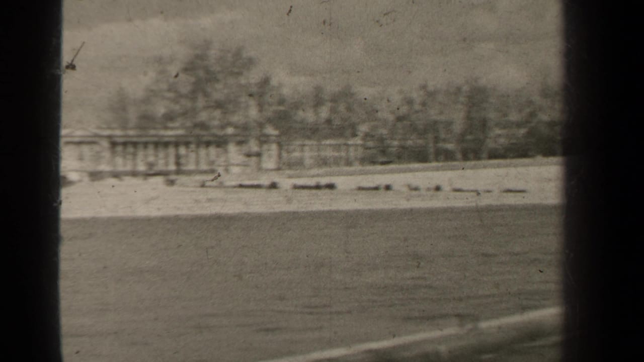 1947 Paris 8mm frame showing a distant classical building across water, with bare trees and dark window-like borders.