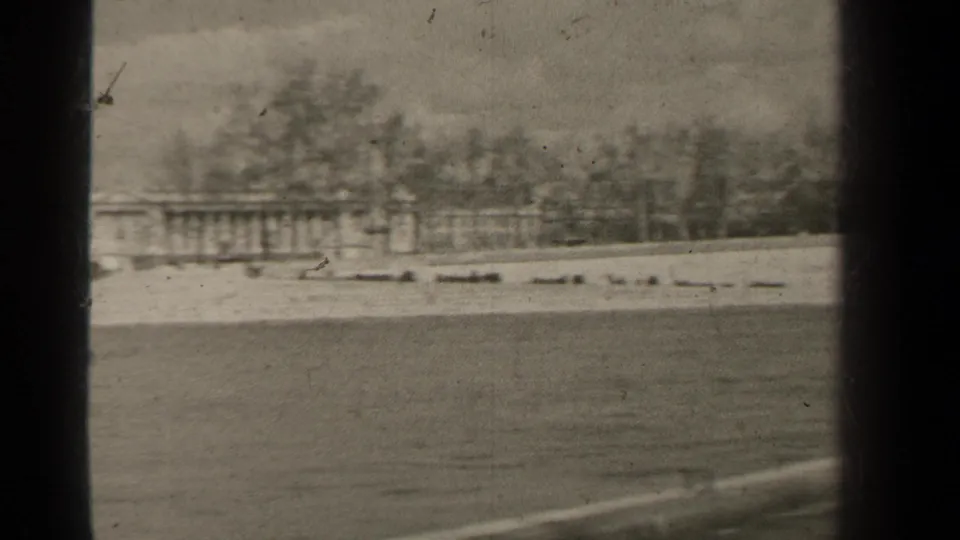 1947 Paris 8mm frame showing a distant classical building across water, with bare trees and dark window-like borders.