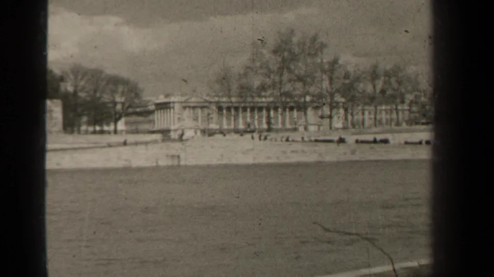 1947 Paris view of a columned waterfront structure, leafless trees, and pale stone embankment across the water.