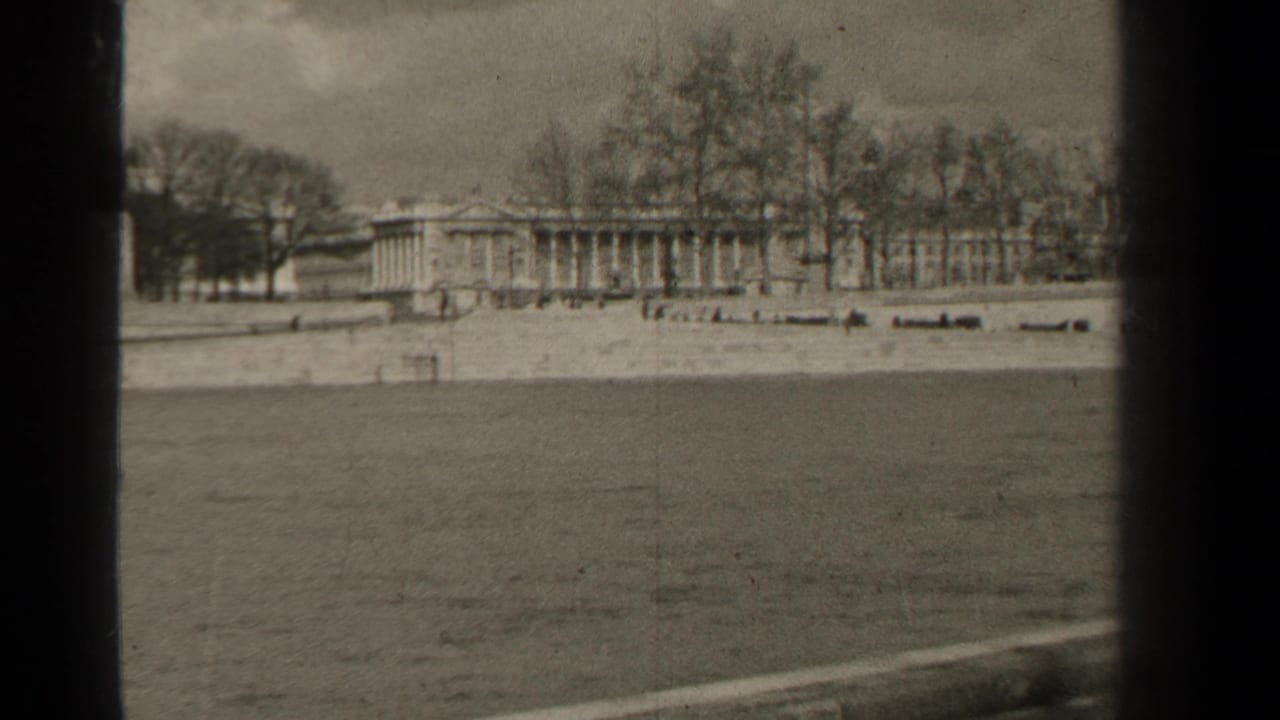 End frame of a 1947 Paris waterfront view, with a long columned building, bare trees, and dark 8mm frame borders.