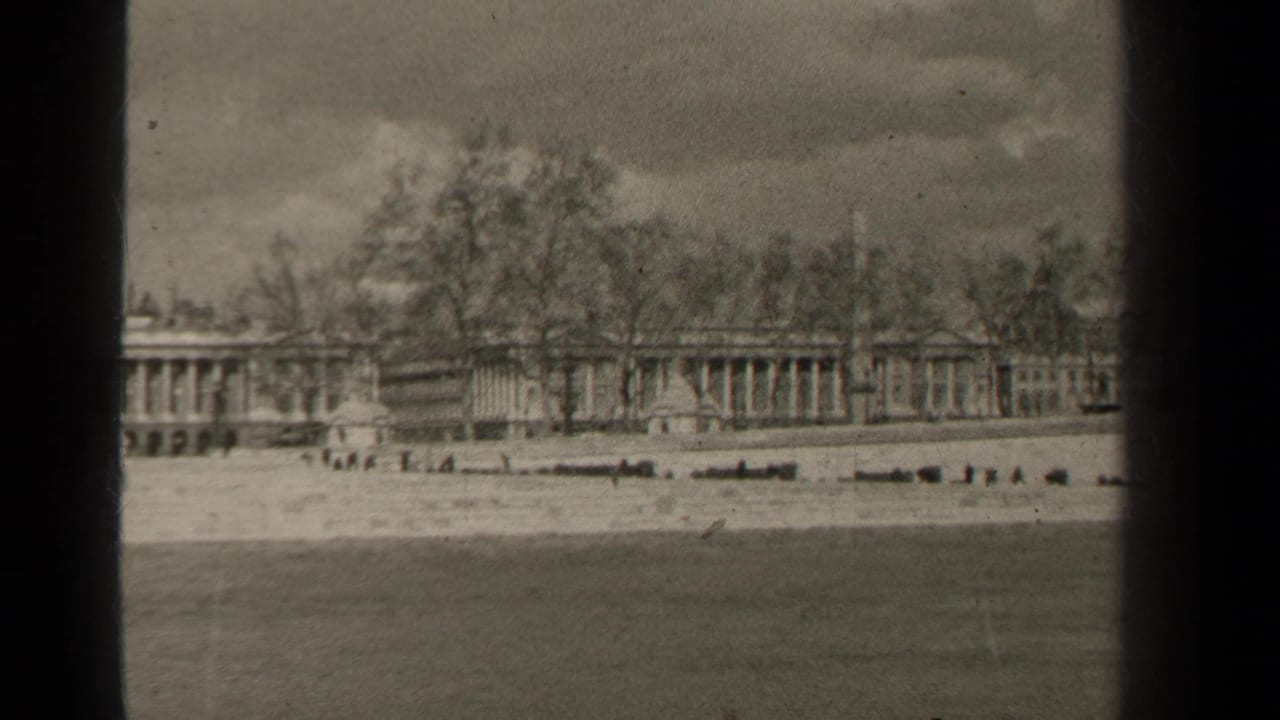 Columned waterfront buildings and bare trees seen beyond a broad stretch of water.