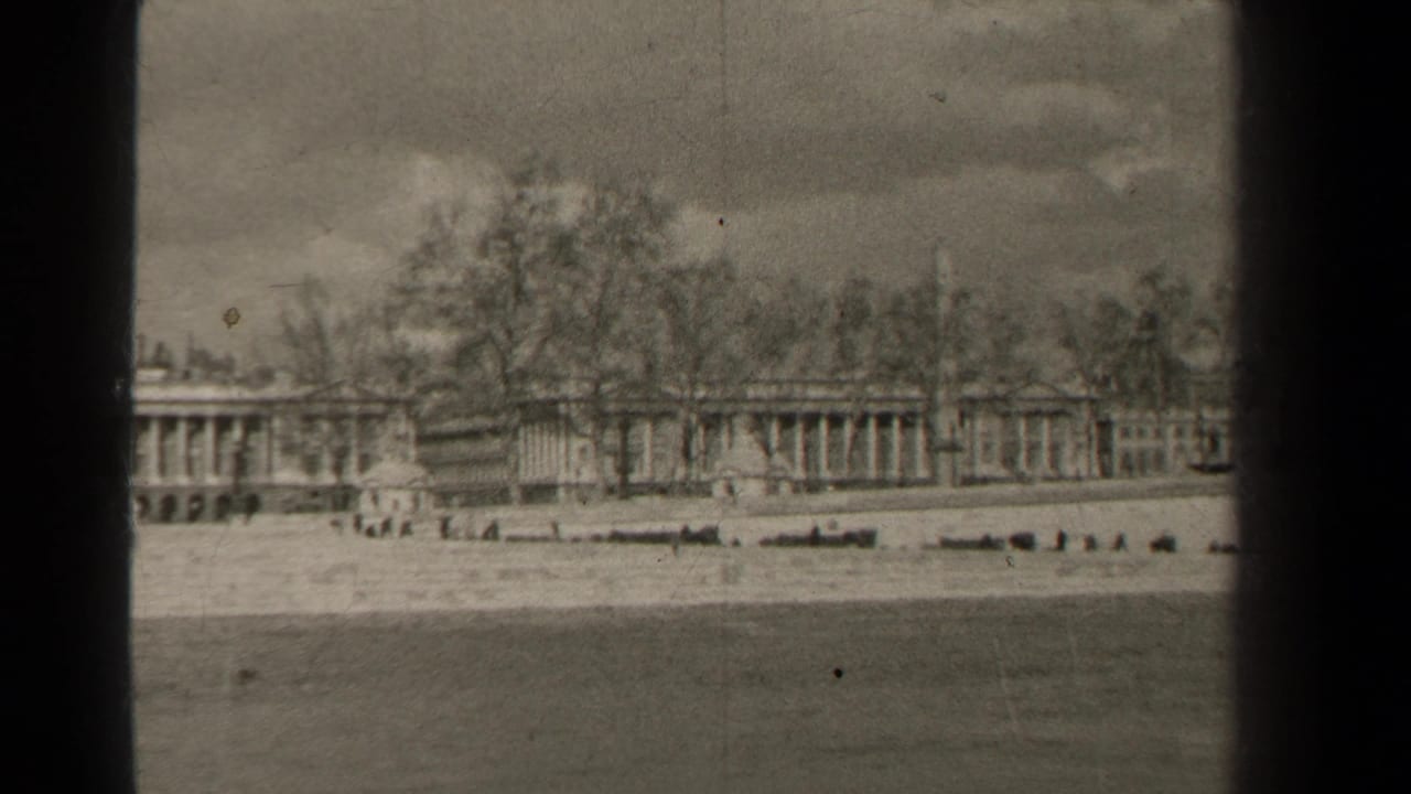 1947 Paris home-movie frame with a low waterfront, distant pedestrians, bare trees, and classical architecture in soft focus.