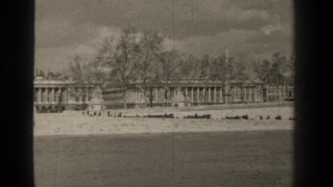 Distant colonnaded building behind an embankment, with water and dark film borders visible.