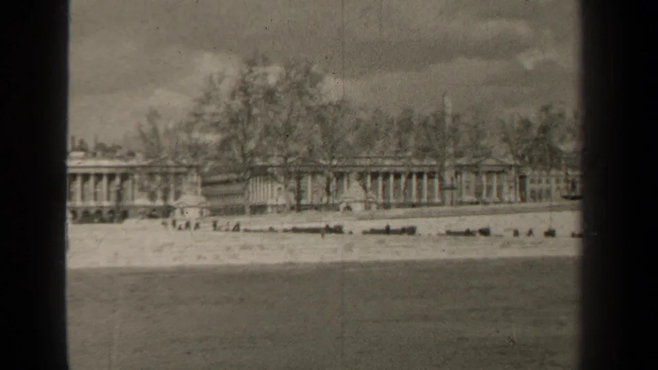1947 Paris frame with a static view across water toward a long colonnaded structure, bare trees, and a cloudy sky.