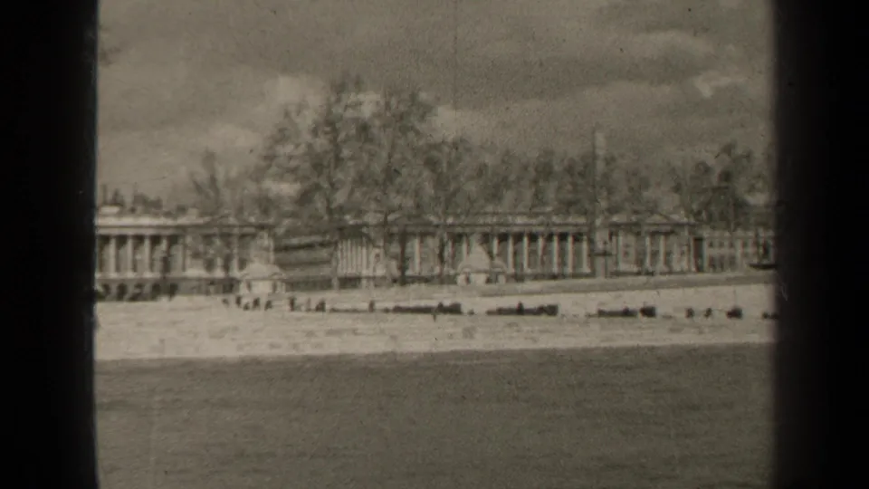 1947 Paris home-movie still showing a soft distant view of formal architecture behind bare trees, seen across water.