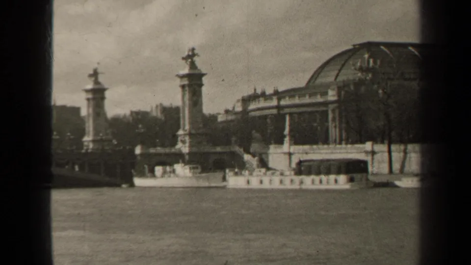A 1947 Paris 8mm frame showing a riverboat on the Seine near Pont Alexandre III, with ornate pylons and a domed building behind.