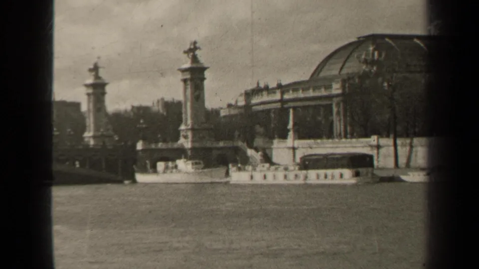 1947 Paris river view with Pont Alexandre III columns, sculptural figures, a glass-domed building, and a boat along the Seine.