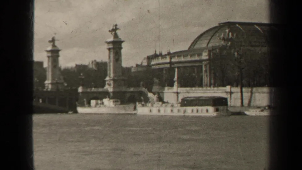 1947 Paris view across the Seine toward ornate stone bridge pylons, statues, leafless trees, and a domed architectural roofline.