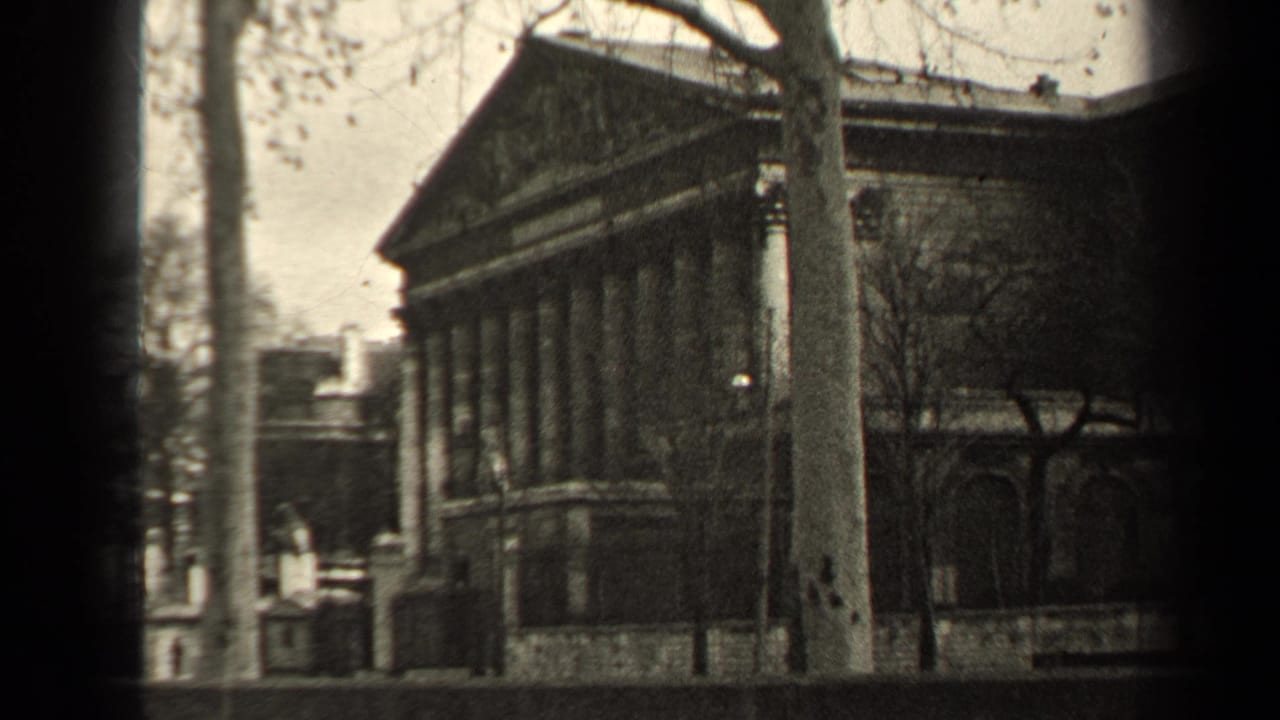 1947 Paris street-side view of a classical stone building with columns and a triangular pediment, partly framed by bare trees.