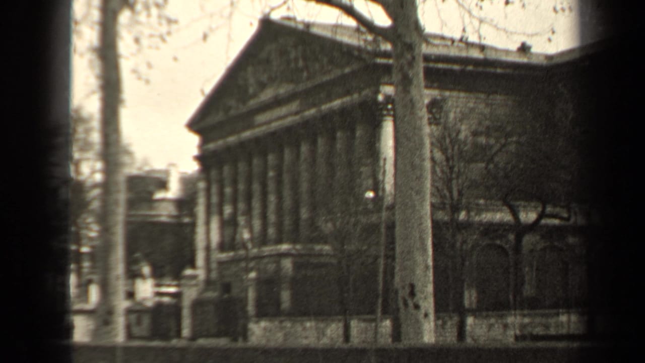 1947 Paris architectural shot showing a classical columned building with a triangular pediment, bare trees, and shadowed masonry details.