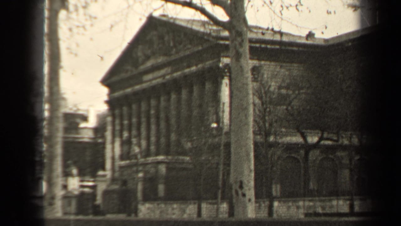 Final 1947 Paris frame showing the columned building, bare trees, street, and dark 8mm frame borders.