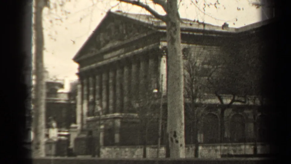 Final 1947 Paris frame showing the columned building, bare trees, street, and dark 8mm frame borders.