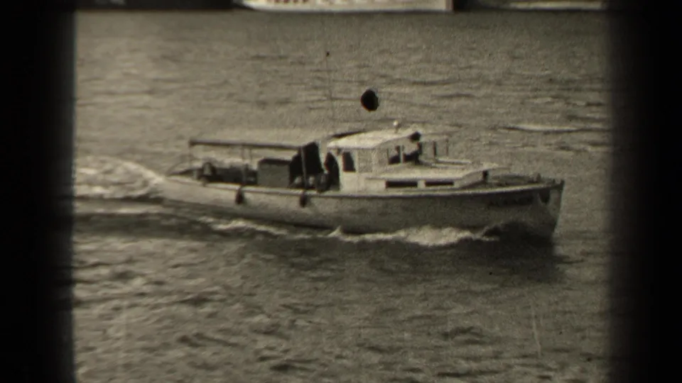 1947 Paris home-movie frame of a small cabin boat traveling along the river, with wake, soft focus, and visible film wear.
