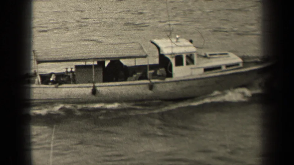The small motorboat continues through the Paris river scene, with cabin windows, deck equipment, and rippling wake visible in soft 8mm focus.