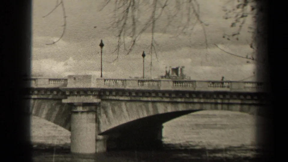 A 1947 Paris home-movie frame shows a stone bridge crossing the river, with lampposts, railings, bare branches, and small distant pedestrians.