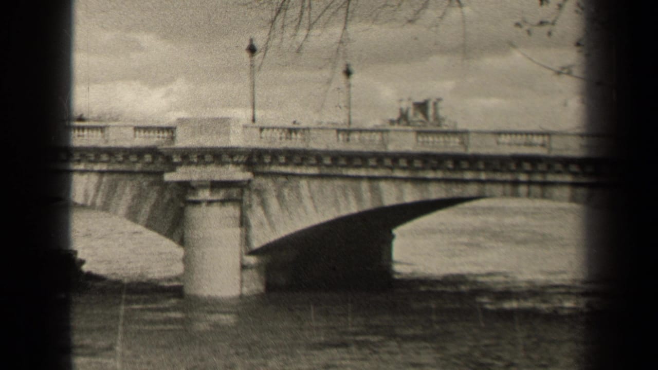 Bridge deck and arch over water, with lampposts, stone railing, and small figures or cars above.