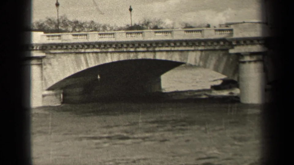 1947 Paris frame showing the boat near the far side of a stone bridge arch, with pedestrians and lampposts silhouetted above.