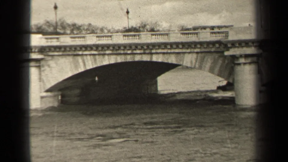 1947 Paris 8mm frame showing a stone river bridge, water, lamps, and dark vertical frame edges.