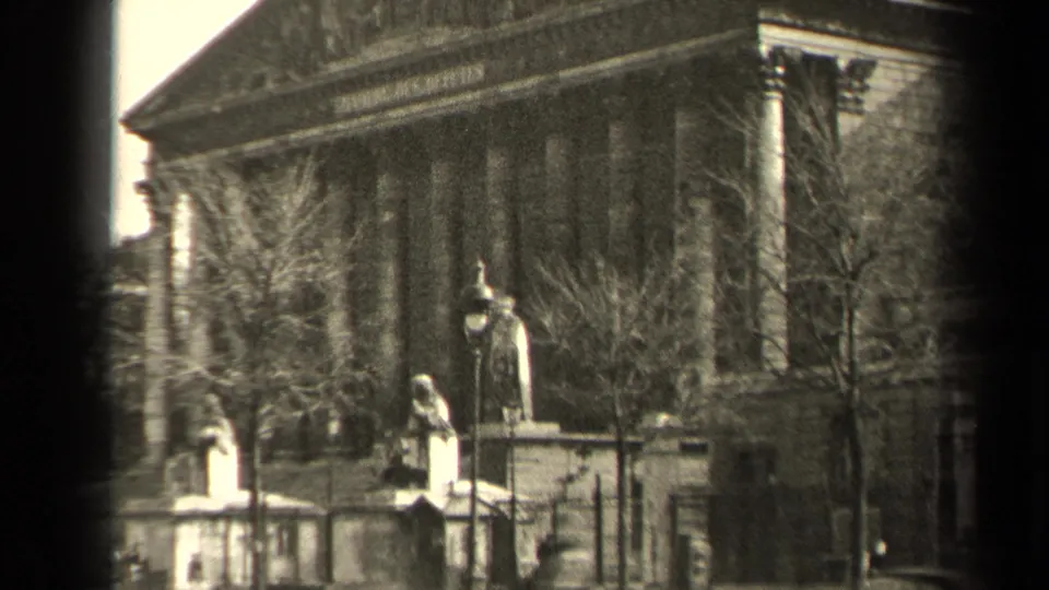 1947 Paris frame with foreground statues, a fenced approach, bare trees, and a neoclassical civic facade.
