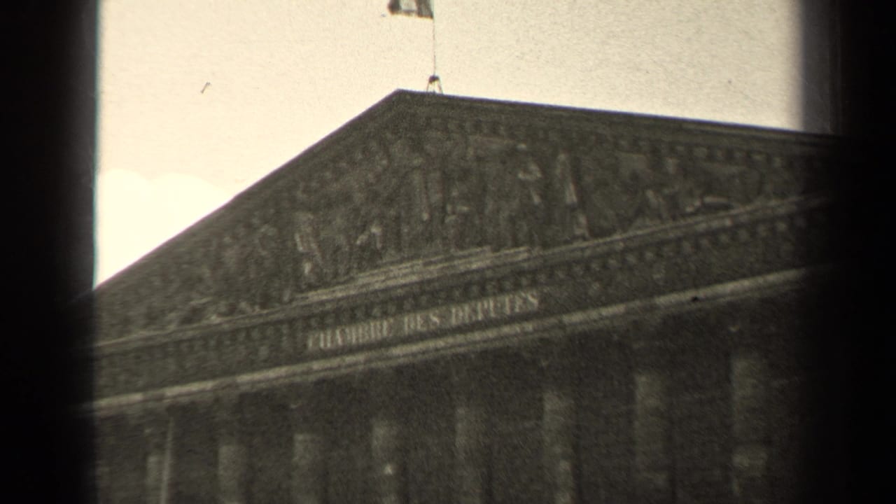 Low-angle view of the Palais Bourbon facade with a flag above the roofline.