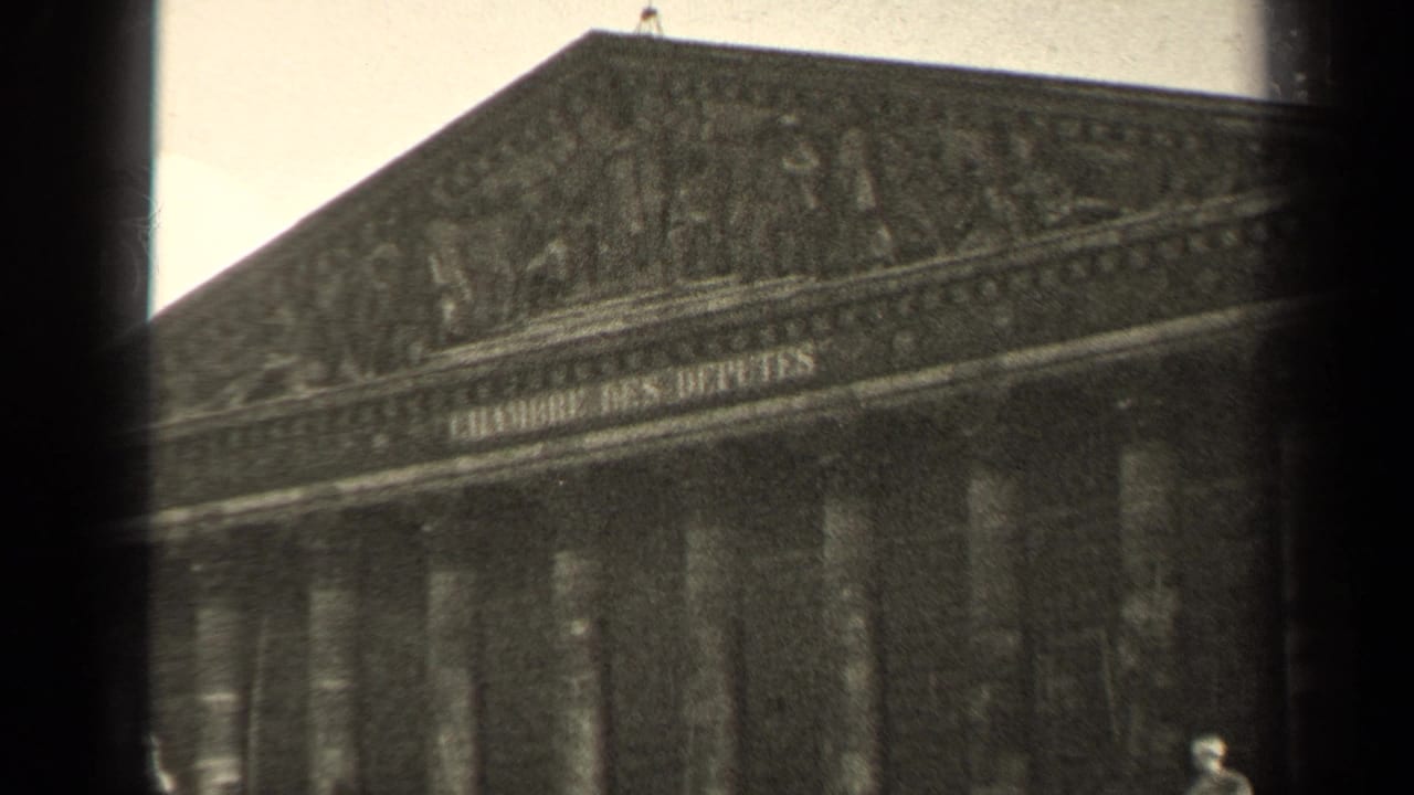 Upper facade of a neoclassical building with columns and carved pediment detail.