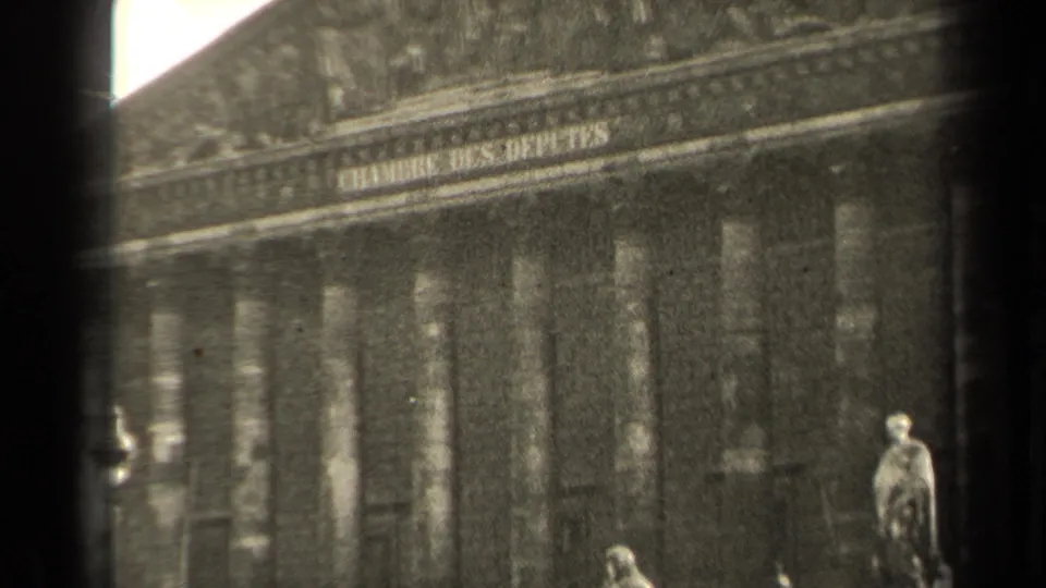 1947 Paris home-movie frame showing the Chambre des Deputes columns, base statues, steps, and a small distant pedestrian.