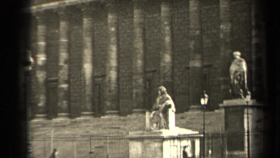 1947 Paris 8mm frame showing a columned historic facade with pedestal statues, railings, and a lamppost.