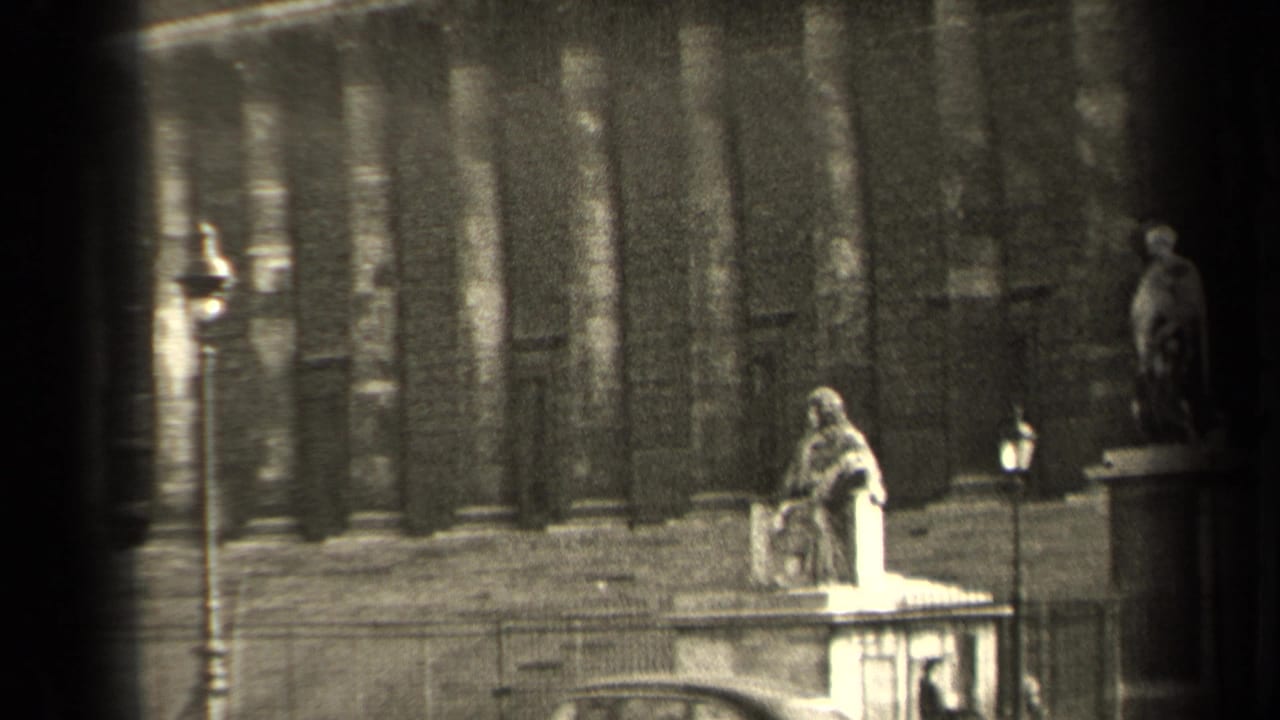 Historic facade with stone statues, lampposts, railings, and dark film edge.