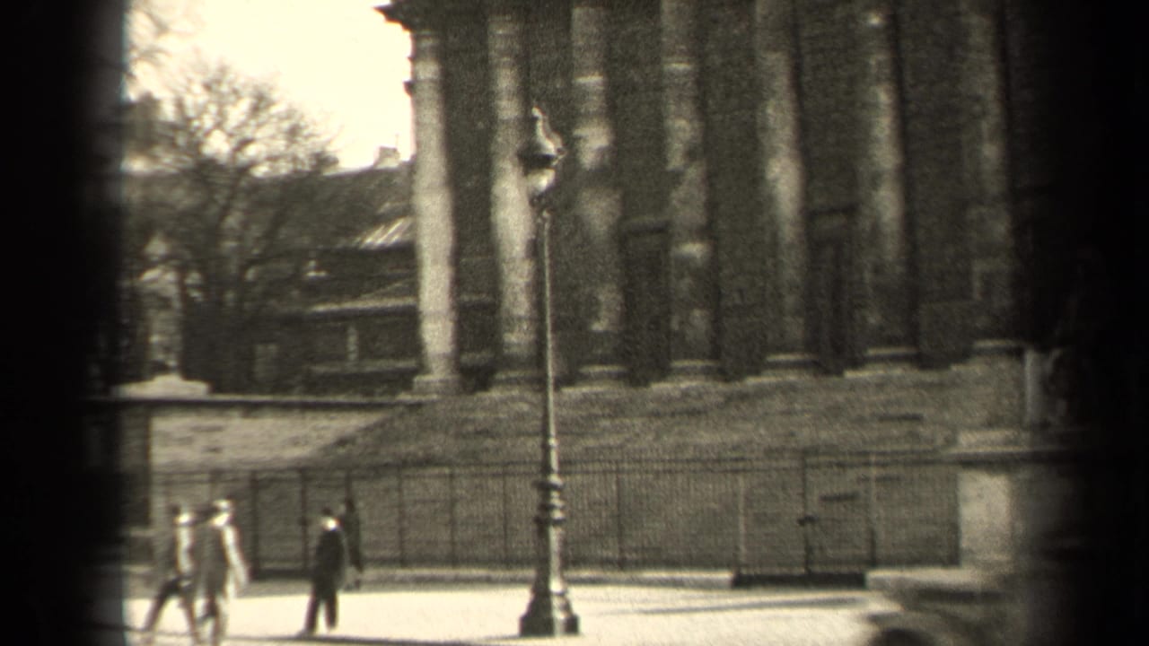 1947 Paris street frame showing pedestrians near railings and a lamppost, with the historic facade continuing behind them.