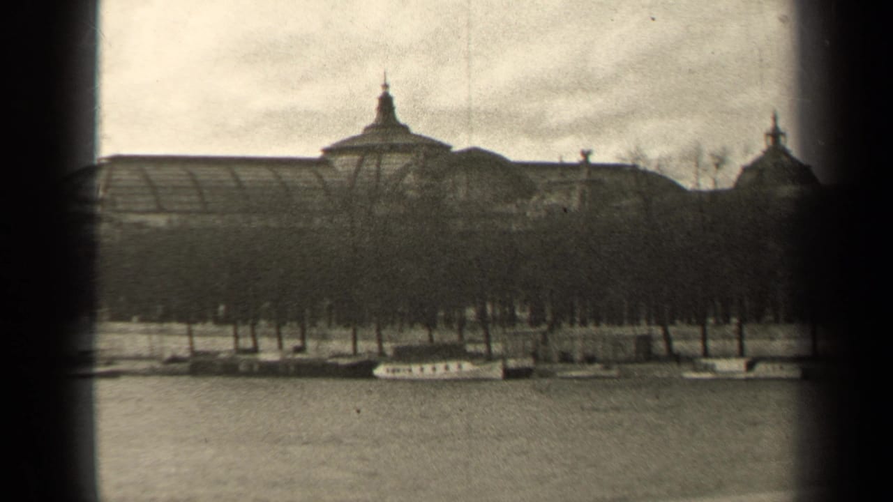 1947 Paris home-movie view of a formal riverfront building partly screened by trees, with boats along the embankment.