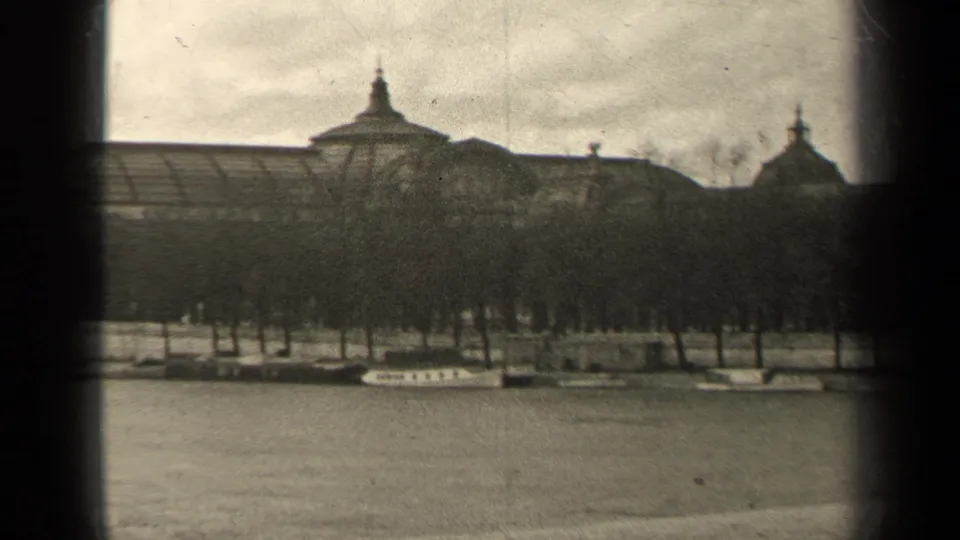 1947 Paris frame showing river water, a line of trees and moored boats beneath a large classical-looking building.