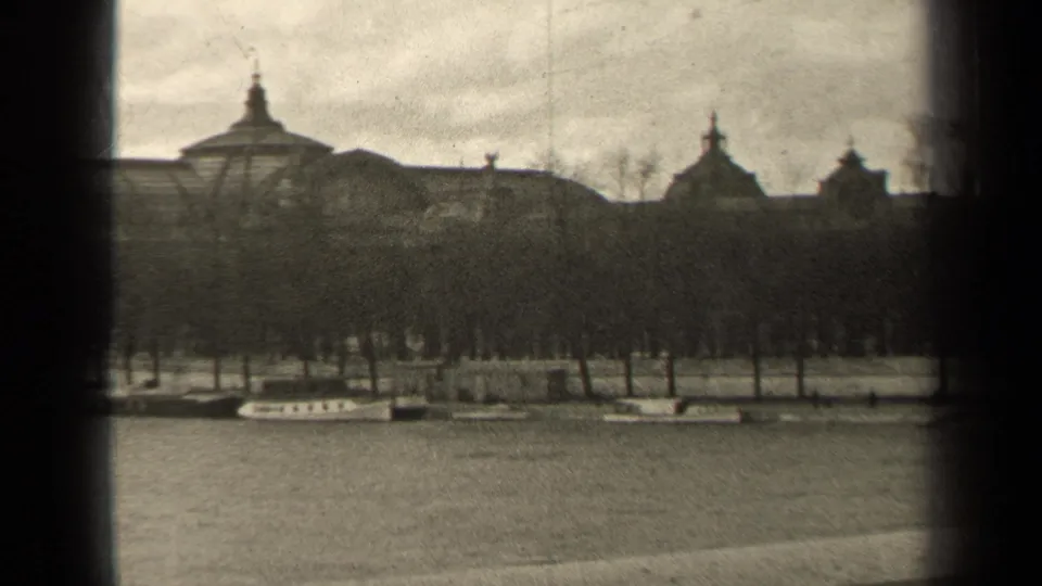 1947 Paris home-movie frame showing a winter park, leafless trees, pale paths, and distant domed rooftops in soft black-and-white 8mm.