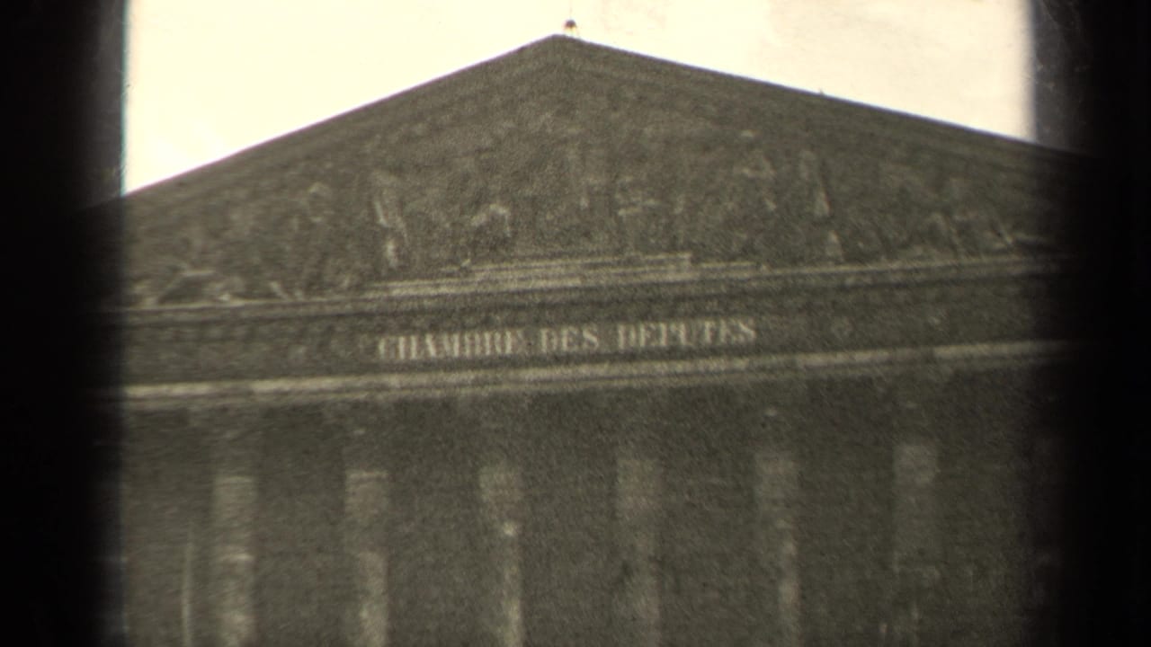 Upper building facade with pediment, inscription, columns, and dark vignette.