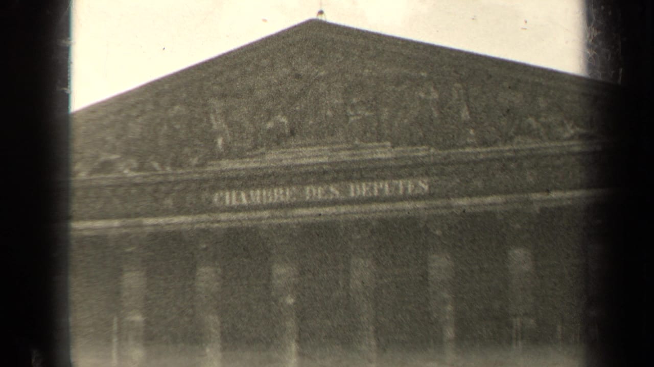 Large stone building seen across the Seine through dark vertical foreground framing.