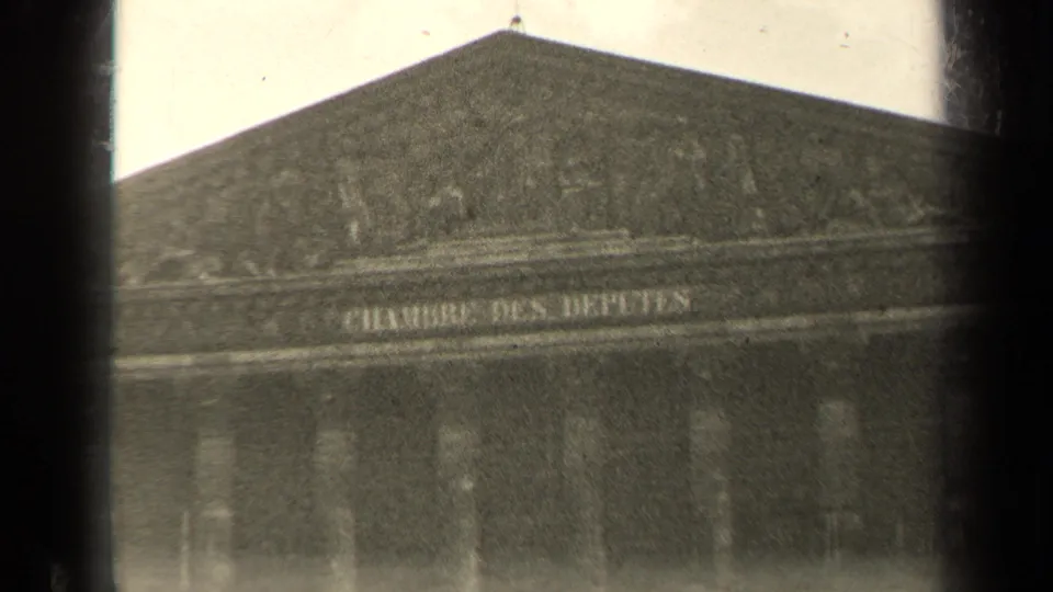 1947 Paris home-movie view of a large civic building across the Seine, partly obscured by dark vertical foreground bars.