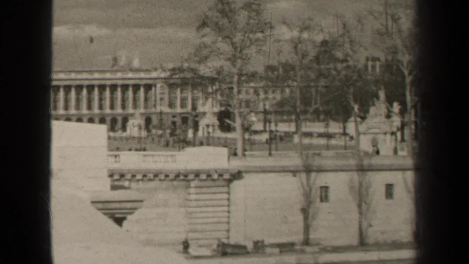1947 Paris frame of a grand classical facade with columns, bare trees, and a stone wall in the foreground.