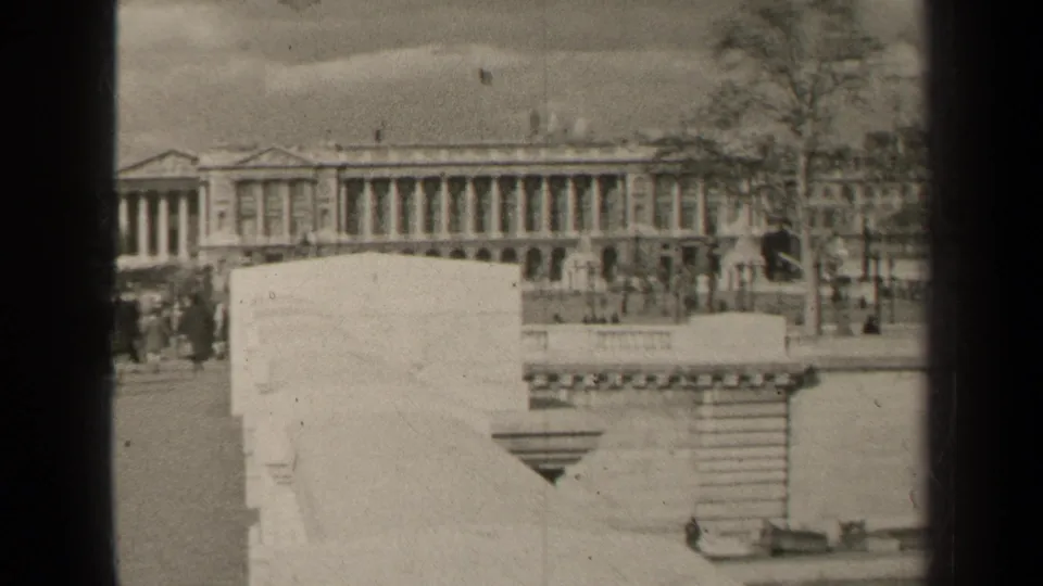 1947 Paris street view with a grand columned facade, low stone walls, trees, and small pedestrians in the distance.