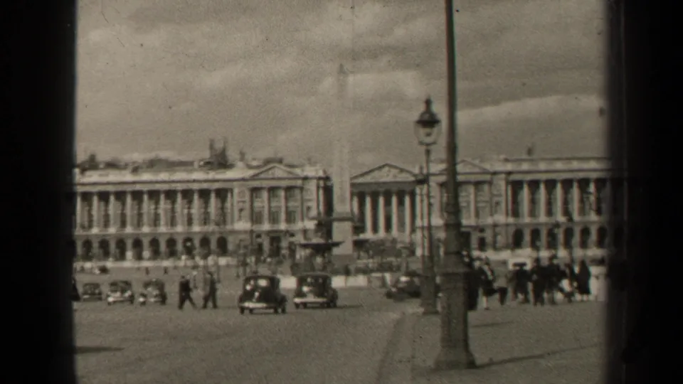 1947 Paris street view with cars, walkers, lampposts, and neoclassical buildings seen through 8mm frame borders.