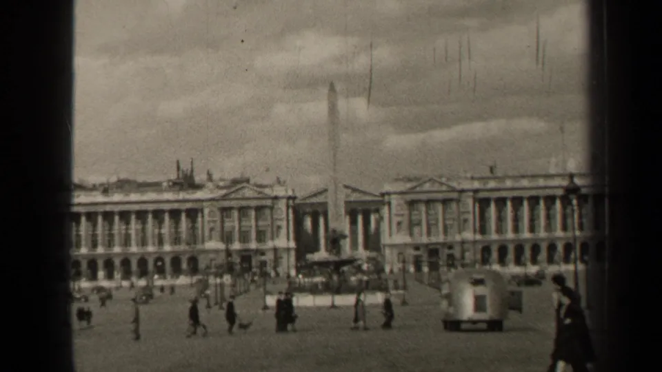 1947 Paris square with a tall obelisk, scattered pedestrians, passing cars, lampposts, and grand neoclassical facades.