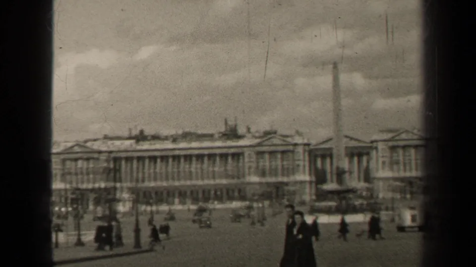 Soft-focus 1947 Paris square view with pedestrians and cars moving across the plaza near an obelisk and neoclassical buildings.