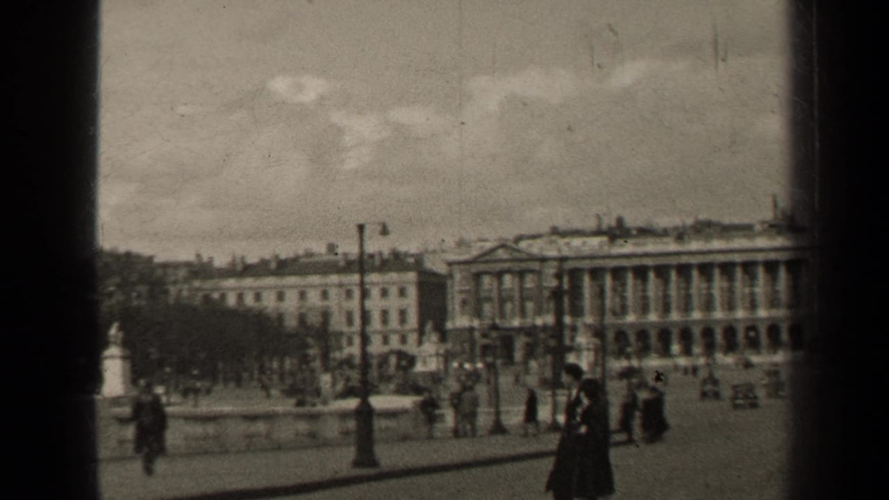 A young couple walks past lamp posts with large civic buildings across the square.