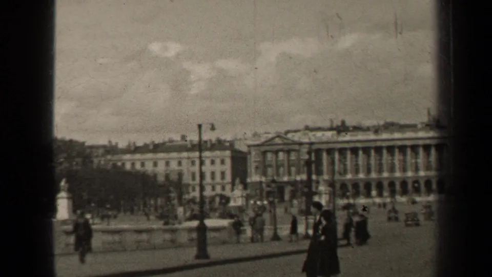 1947 Paris frame with a young couple walking in the foreground and neoclassical buildings lining the distant square.