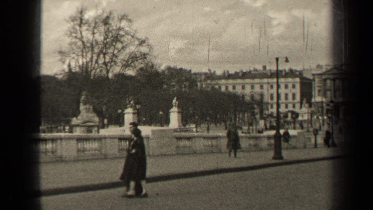 1947 Paris street view with pedestrians in coats, a wide paved walkway, bare trees, lampposts, and classical buildings in the distance.