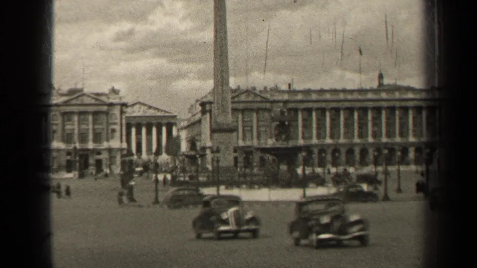 1947 Paris view of automobiles crossing a wide square with pedestrians, an obelisk, lampposts, and monumental stone facades.