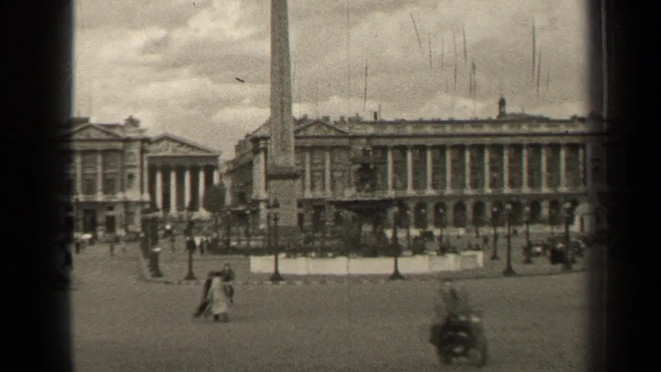 1947 Paris home-movie view of a broad public square with an obelisk, classical facades, pedestrians, and sparse vehicles.