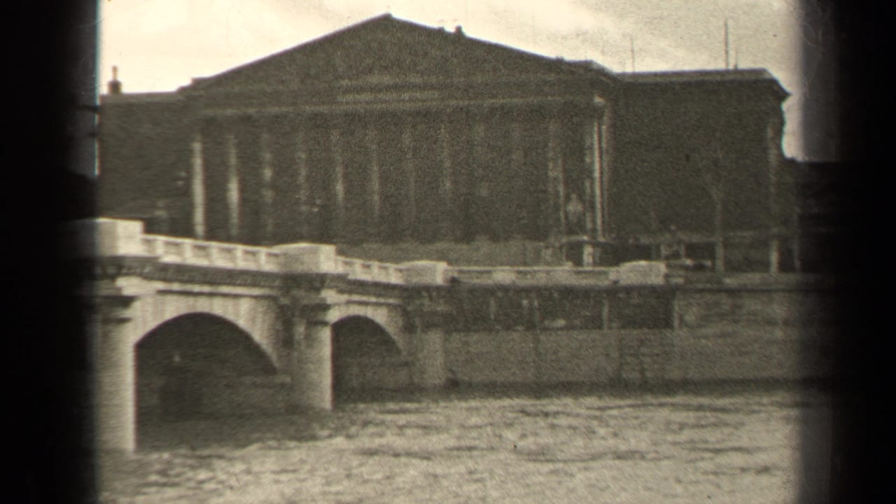 1947 Paris home-movie frame showing a stone river bridge and a large classical building beyond the embankment.